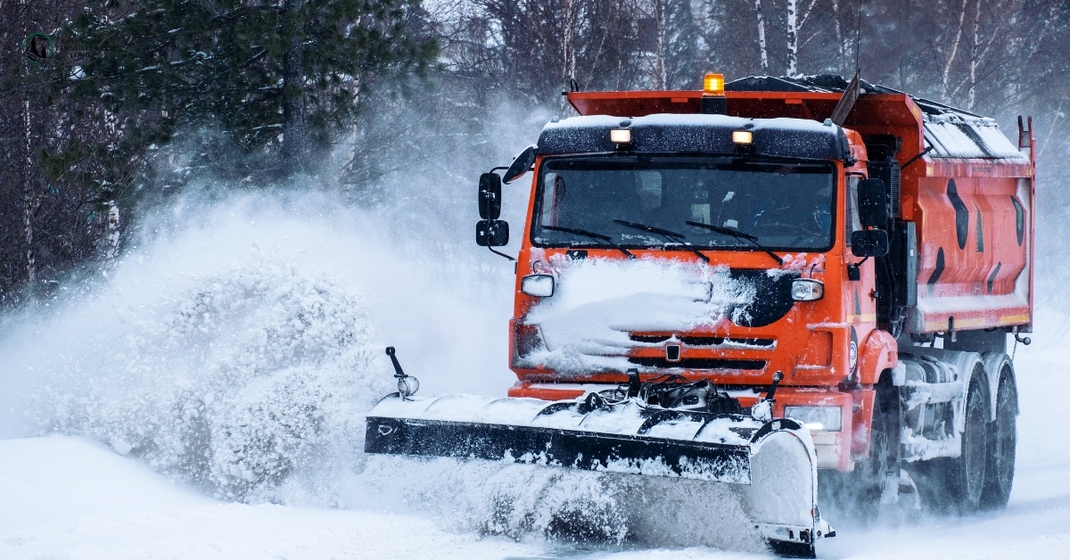 Commercial snow plow clearing snow from an industrial warehouse parking lot in Utah