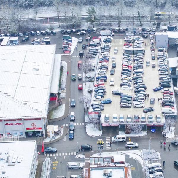 Snow-covered shopping mall parking lot being cleared